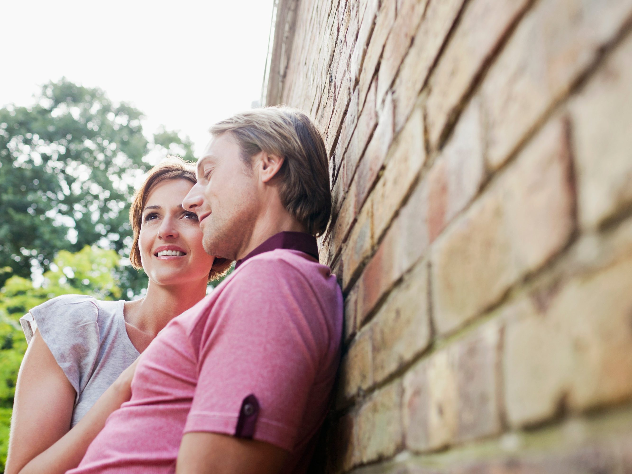Young loving couple leaning against brick façade